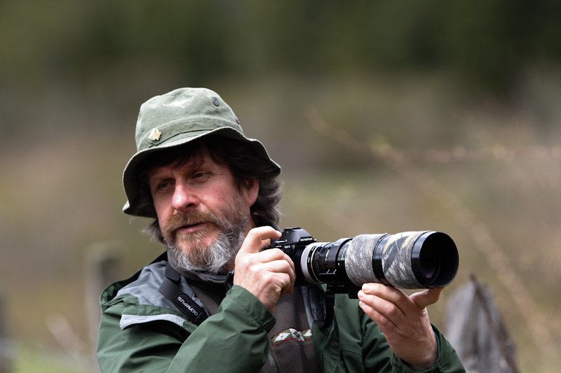 Retrato de Juan Carlos Gedda con cámara fotográfica en entorno natural